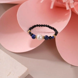 Detail of beaded natural stone ring with pearl and 18K gold plated beads on floral backdrop