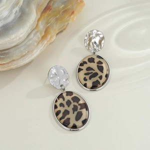 Dettaglio degli orecchini leopardati ovali con borchie in metallo martellato argento