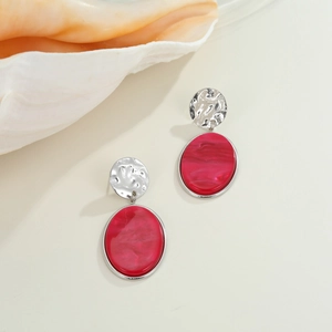 Primo piano dei dettagli degli orecchini effetto marmo con metallo argento e resina rossa
