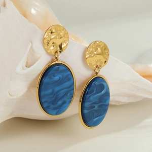 Orecchini vintage in metallo dorato martellato e resina marmorizzata blu su una conchiglia