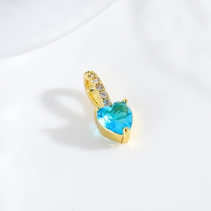 Macro shot of 18k gold plated heart pendant with blue gemstone and sparkling diamonds