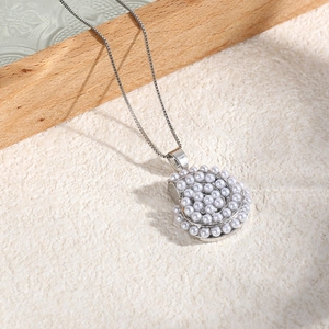 Detailed close-up of conch shell pendant with white pearls on a box chain necklace