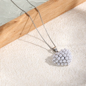 Detail of elegant heart-shaped pearl pendant necklace on a natural stone base