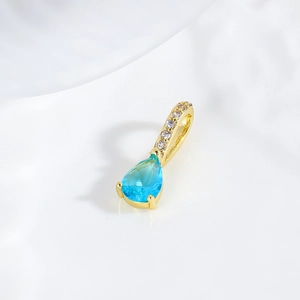 Macro detail of teardrop blue zircon pendant with 18k gold plating and pave diamonds