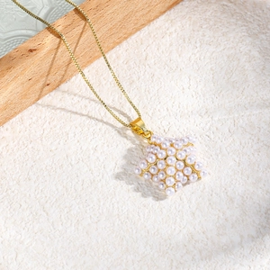 Detail of star-shaped pearl pendant on a gold box chain with polished metal texture