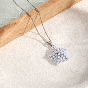 Detailed view of elegant star-shaped pendant encrusted with small white pearls on silver chain