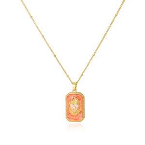 Macro detail of golden sacred heart tarot pendant with orange glitter enamel on a satellite chain
