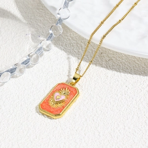 Detail view of a vintage tarot heart pendant with orange glitter and a gold bead chain