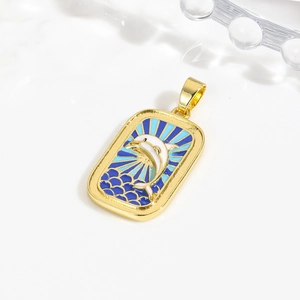 Detail of gold enamel tarot pendant featuring a white dolphin and blue ocean waves