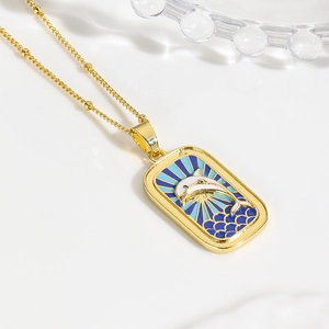 Detail of gold-plated ocean dolphin pendant with blue enamel and small bead chain