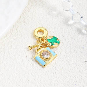 Macro detail of gold travel charms including camera, globe, and airplane pendants