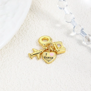 Detailed view of travel charms featuring a golden airplane, pink heart, and suitcase pendant