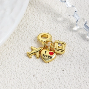 Macro shot of gold travel charms featuring an airplane, suitcase and heart luggage tag