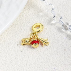 Detailed close-up of gold travel charms including camera, red globe, and airplane pendants