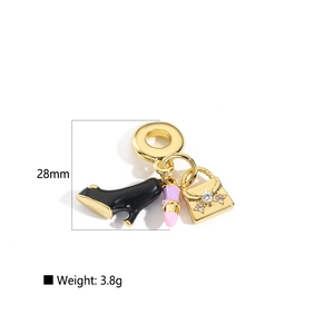 Detailed macro of gold charm pendant featuring high heel, lipstick, and handbag charms