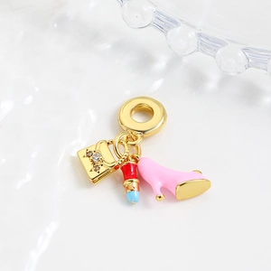 Macro detail of three enamel charms including high heels, lipstick, and a handbag