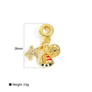 Macro detail of nautical gold charms with starfish, sailboat, and rudder pendants