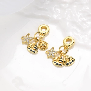 Macro view of gold nautical charms with blue enamel sailboats and crystal starfish