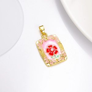 Détail d'un pendentif rose rectangulaire doré avec émail rose et une perle au centre