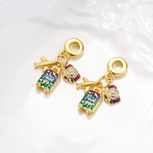 Golden travel charms featuring a plane, camera, and 'Just go!' suitcase with enamel