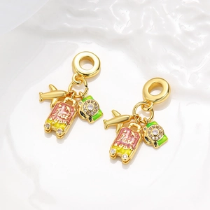 Detail of gold charms including a suitcase with 'Just go' text and colorful enamel cameras
