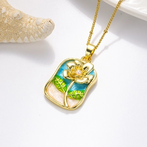 Détail du pendentif émaillé doré avec fleur jaune, perle centrale et feuilles vertes