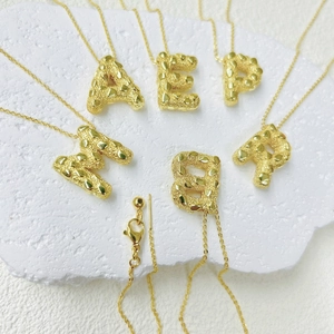Detail van de onregelmatige 18k vergulde alfabet hangers met gesmolten lava textuur