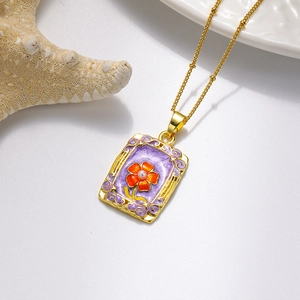 Gros plan du pendentif floral rectangulaire en émail avec perle et chaîne dorée