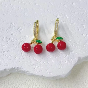 Detalle de los pendientes de cereza dorados con frutas rojas y cristales brillantes