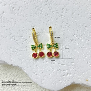 Detalle de pendientes de cereza en cobre dorado con pavé de circonitas rojas y verdes