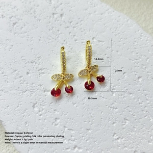 Detalle macro de pendientes de cereza con circonitas rojas y cobre bañado en oro