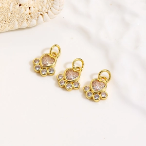 Detailed macro shot of three 18k gold plated dog paw pendants with zircon inlay