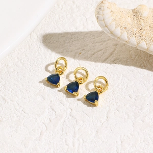 Detailed view of three deep blue triangle zircon pendants with gold metal ring connectors