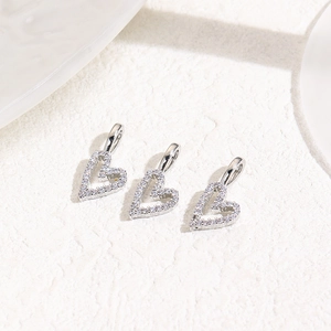 Macro detail of three heart-shaped charms with pave-set cubic zirconia on stone background