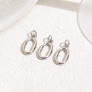 Close-up of three polished oval metal pendant charms for DIY jewelry making