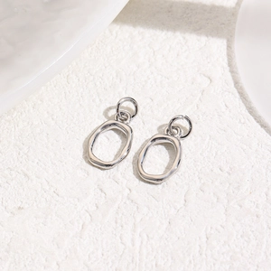 Detail of silver oval charms with unique hammered texture and shiny metallic finish