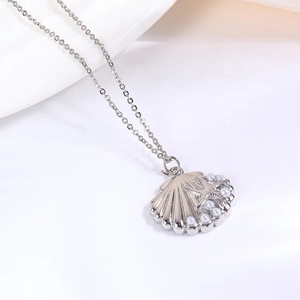 Detail van zilveren schelphanger met zeester-reliëf en witte parels aan een schakelketting