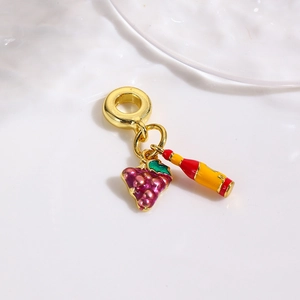 Detail view of gold charm set with purple grape and wine bottle enamel pendants