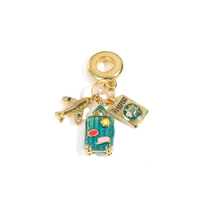 Macro detail of gold-plated travel pendants with enamel suitcase and passport charms