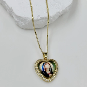 Detailed macro view of heart-shaped gold necklace with Virgin Mary portrait and crystal stones