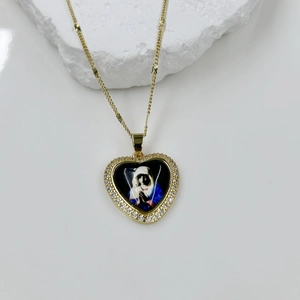 Detail of a gold heart pendant with crystal border and religious icon on a stone