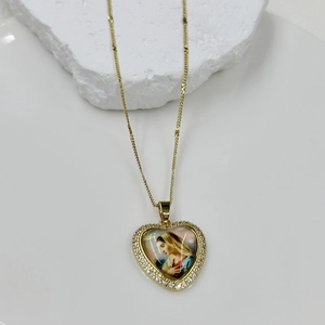 Detailed view of heart-shaped gold necklace pendant with Mary icon and zircon stones