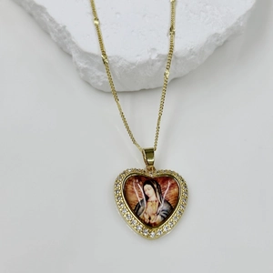 Detailed close-up of a gold heart pendant with Virgin Mary icon and zircon inlay