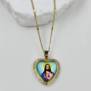 Macro detail of a heart-shaped Virgin Mary pendant with sparkling zircons on a white stone