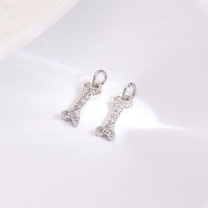 Close-up of bone-shaped silver charms with sparkling pavé zircons for DIY jewelry