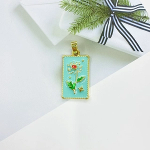Close-up of golden rectangular tarot pendant with floral enamel and beaded edge detail