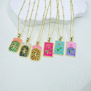 Macro view of tarot-style gold enamel square pendants with mushroom and rose patterns
