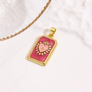 Macro detail van gouden tarot hanger met rood emaille en roze hart met oogmotief