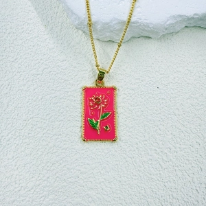 Detail view of a pink enamel rose tarot pendant on a delicate gold beaded chain