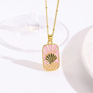 Macro-opname van een gouden kralenketting met roze emaille hanger op een witte tafel